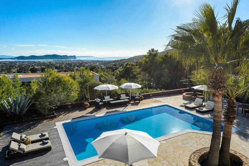a villa with a swimming pool with an umbrella at Villa Arcadia in Ibiza Town