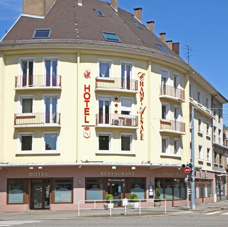 un gran edificio amarillo con un letrero rojo. en Hotel Champ Alsace, en Haguenau