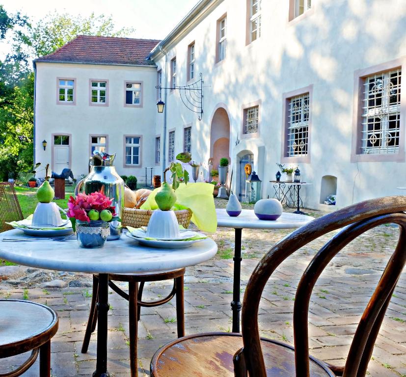 een patio met 2 tafels en stoelen en een gebouw bij Event- Kultur & B&B Kunst Schloss Neuenhagen Übernachten im Denkmal in Bad Freienwalde