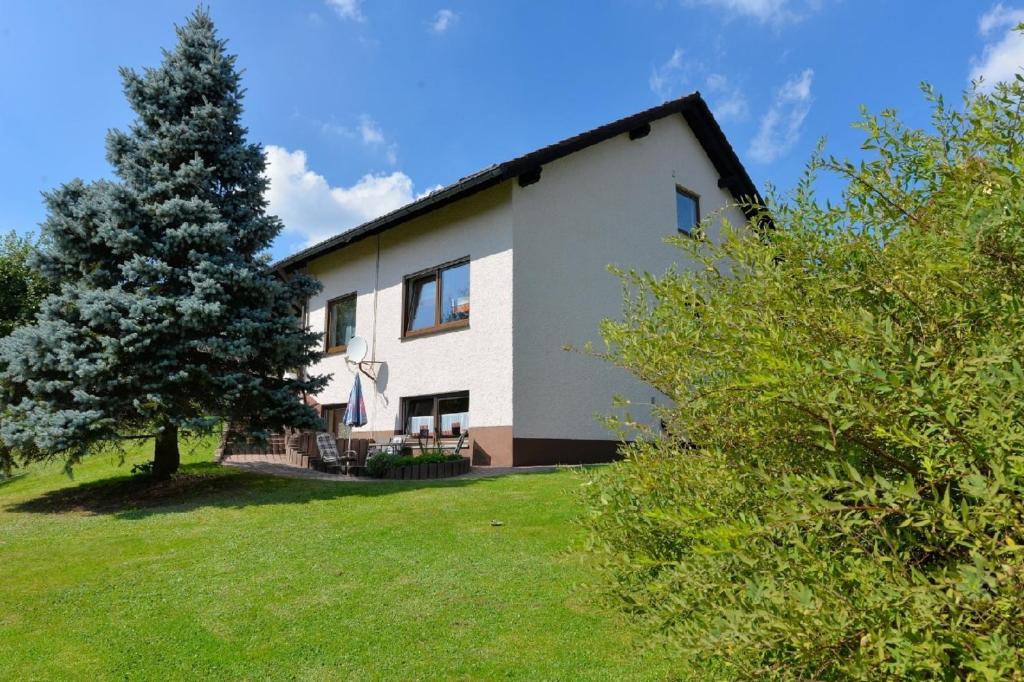 a white house with a tree in the yard at Ferienwohnung Brunner - Haus am See in Nagel