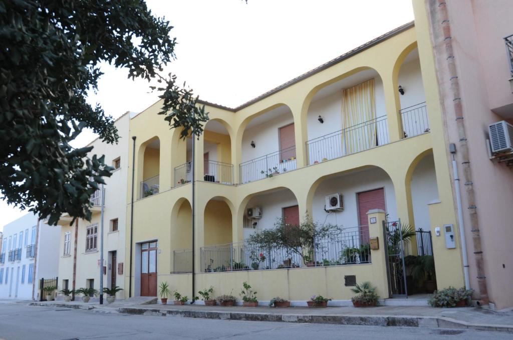 un grande edificio giallo con balconi su strada di case vacanze Rosy a San Vito lo Capo