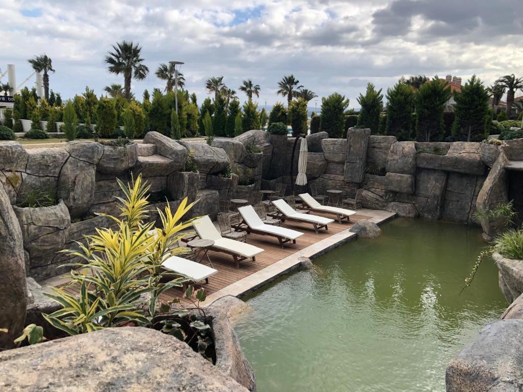 a group of lounge chairs sitting on a wooden bridge over a pond at Ilica Hotel Spa & Wellness Resort in Çeşme