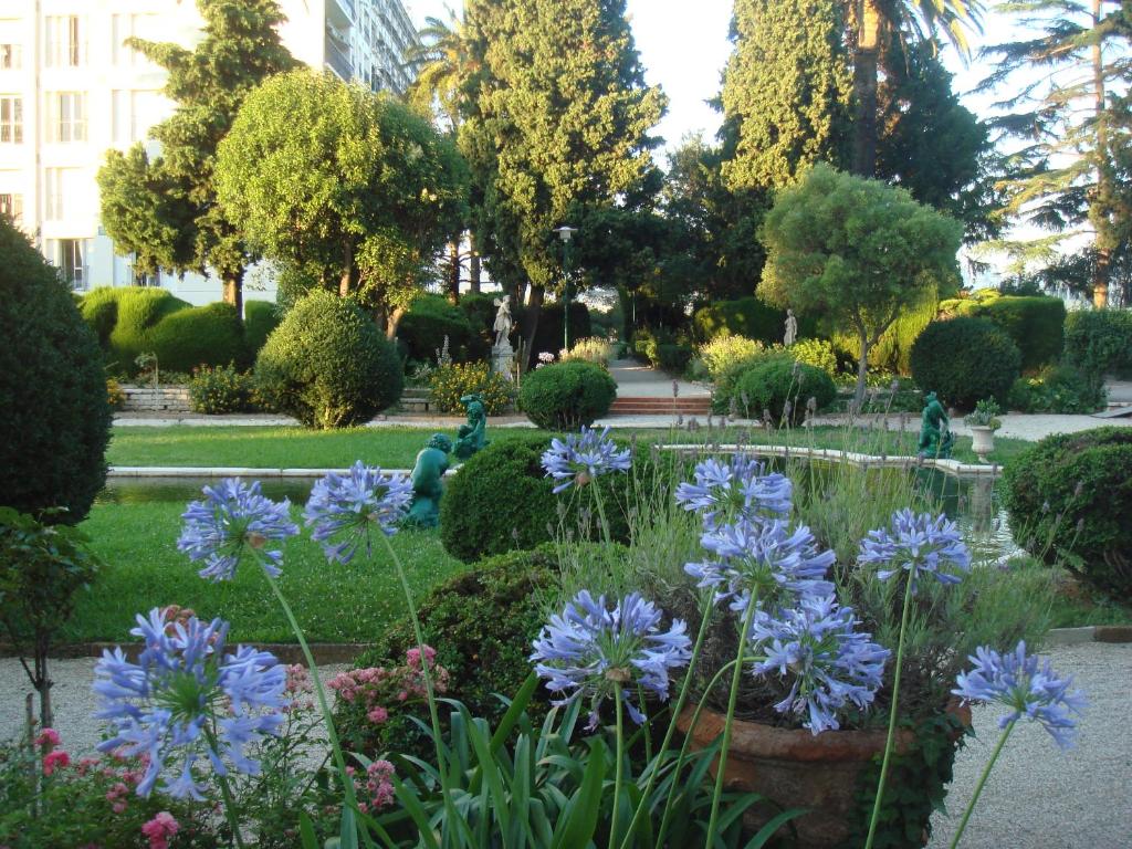 a garden with blue flowers and a fountain at LES GRANDS CEDRES C1 7 Avenue de Fabron in Nice