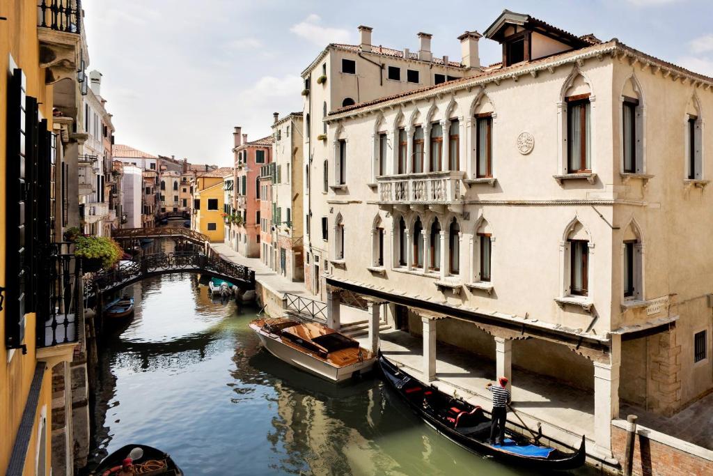 a view of a canal between two buildings with gondolas at Maison Venezia | UNA Esperienze in Venice