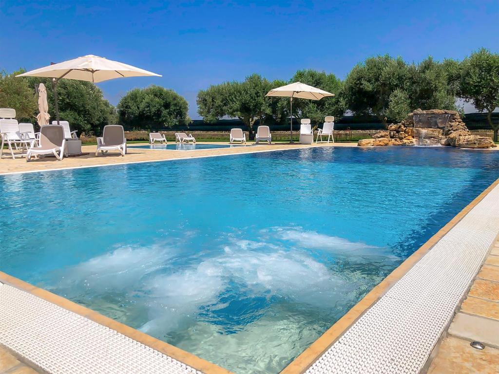 a large swimming pool with chairs and umbrellas at Terra dei Sogni in Torre Lapillo