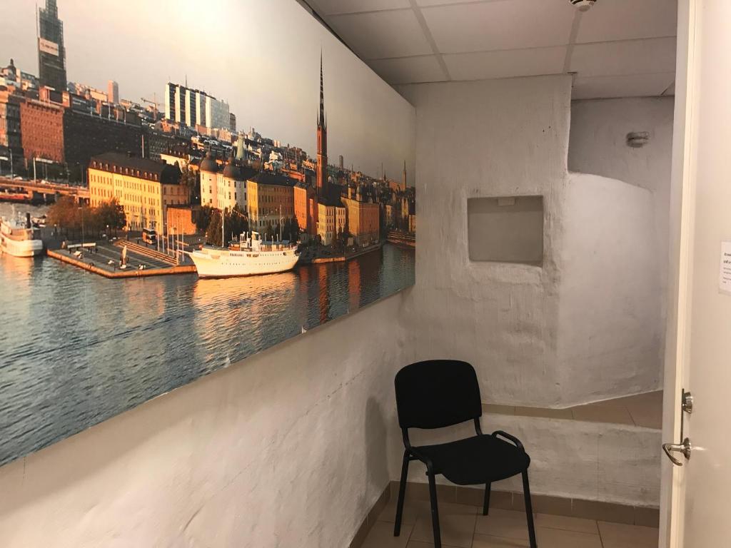 a chair in a room with a painting of a city at Hostel Dalagatan in Stockholm