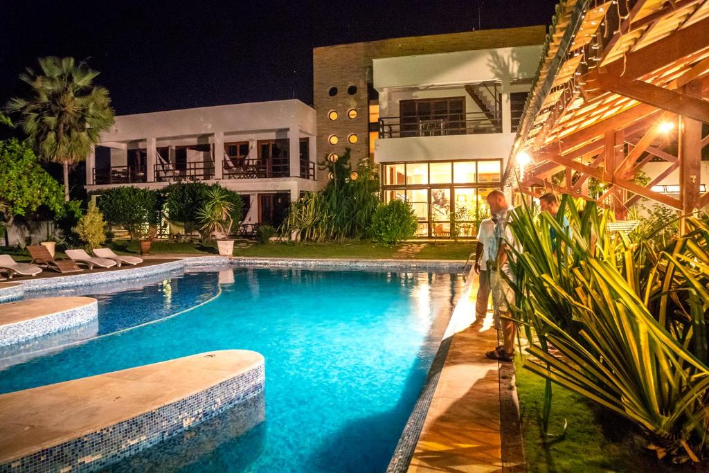 a man standing next to a swimming pool at night at Refúgios Parajuru in Parajuru