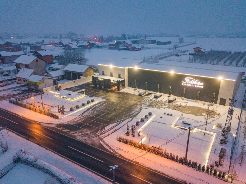 un grande edificio con neve sul suolo e luci di Motel Felikitas a Laktaši