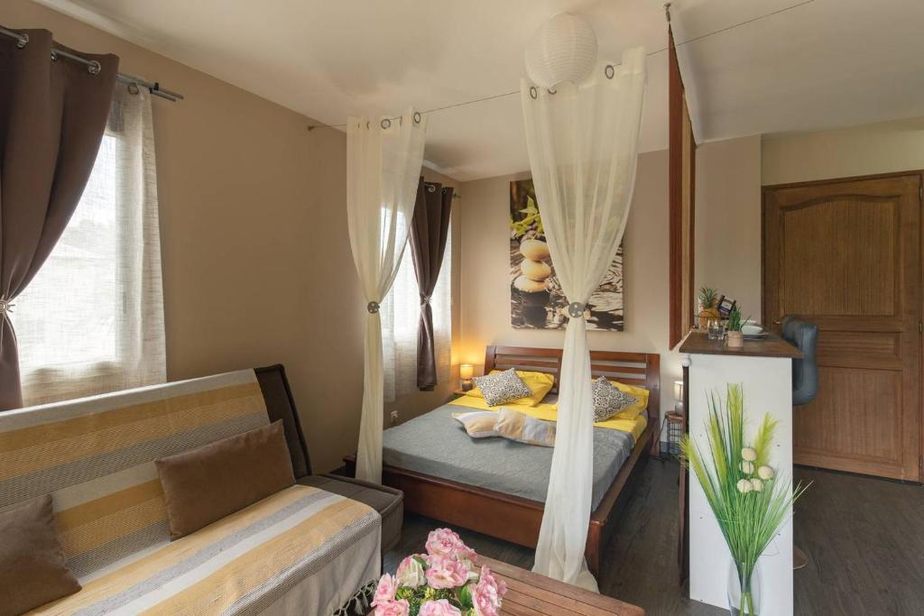 - une chambre avec un lit et un canapé dans l'établissement La Kazette - Votre Studio de Vacances à l Île de La Réunion, à Saint-Louis