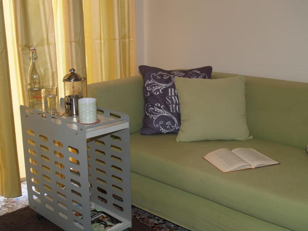 um sofá verde com uma almofada e um livro em The Ideal House In The City Center em Veria