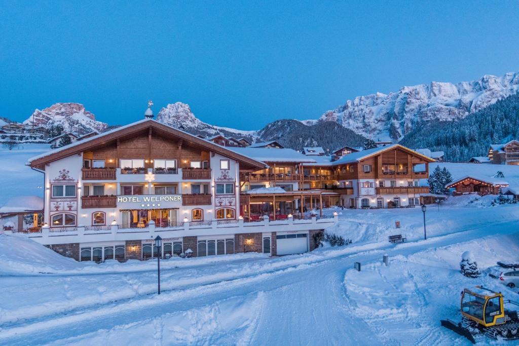 un hôtel dans les montagnes avec de la neige au sol dans l'établissement Hotel Welponer, à Selva di Val Gardena