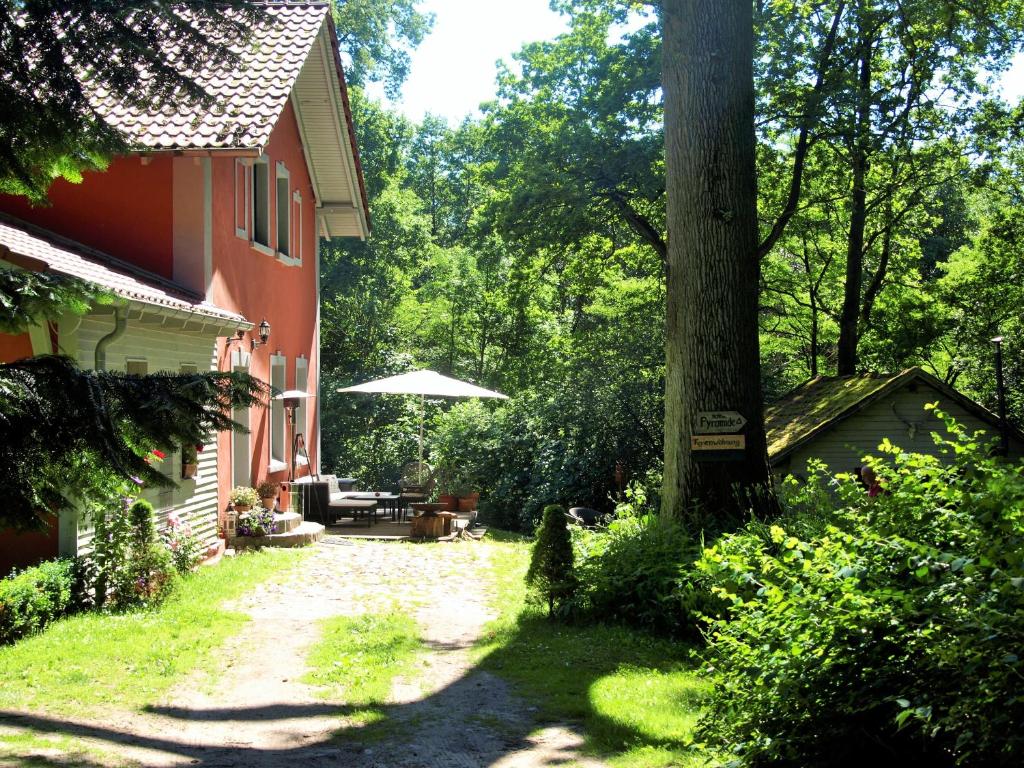 einen Garten neben einem Haus mit Sonnenschirm in der Unterkunft Altes Forsthaus Garzau in Garzau