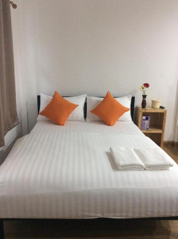 a bed with orange and white pillows on it at Happy Hostel in Bangkok