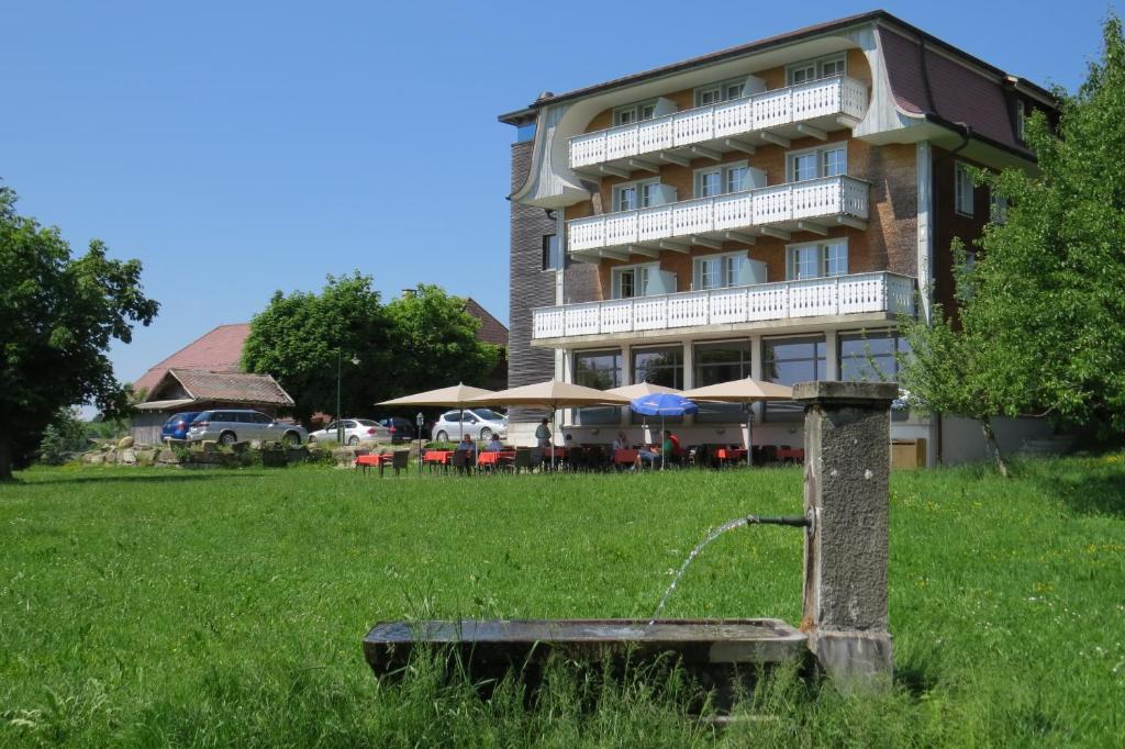 a building with a water fountain in the middle of a field at Hotel Restaurant Sternen in Guggisberg