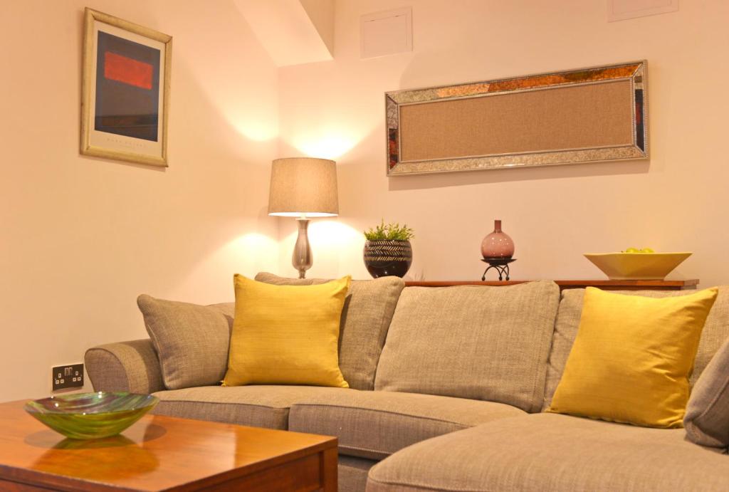 een woonkamer met een grijze bank en gele kussens bij The Sanctuary in Eastbourne