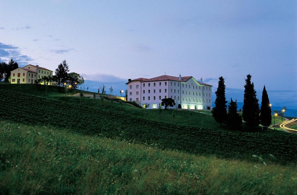 a large white building on a hill with trees at Phi Hotel Astoria in Susegana