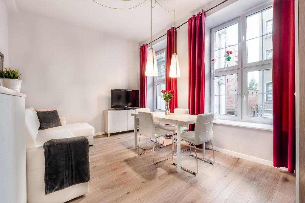 a living room with red curtains and a table and chairs at Golden Gate by Loft Apartments in Gdańsk