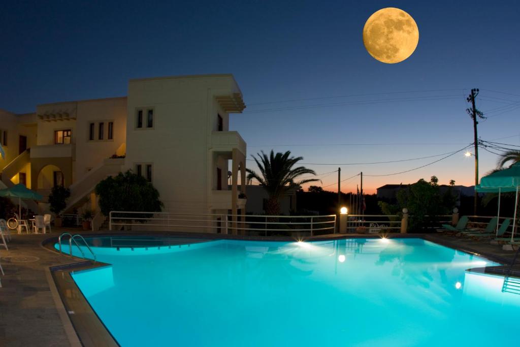 luna llena sobre una piscina por la noche en Olga Suites, en Máleme