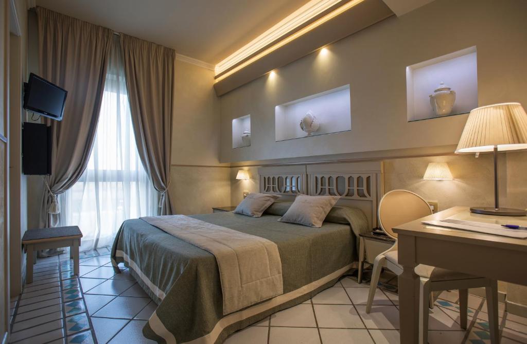 a hotel room with a bed and a desk at Hotel Hermitage in Galatina