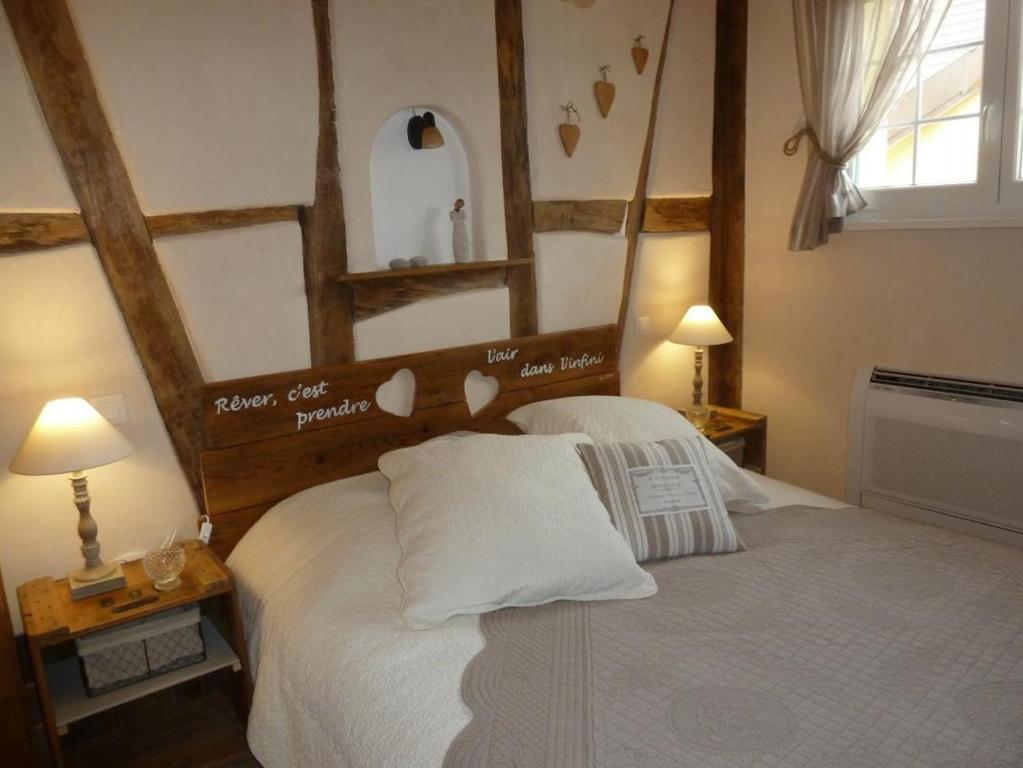 a bedroom with a white bed with a wooden headboard at L'Alcôve des p'tits coeurs in Benfeld