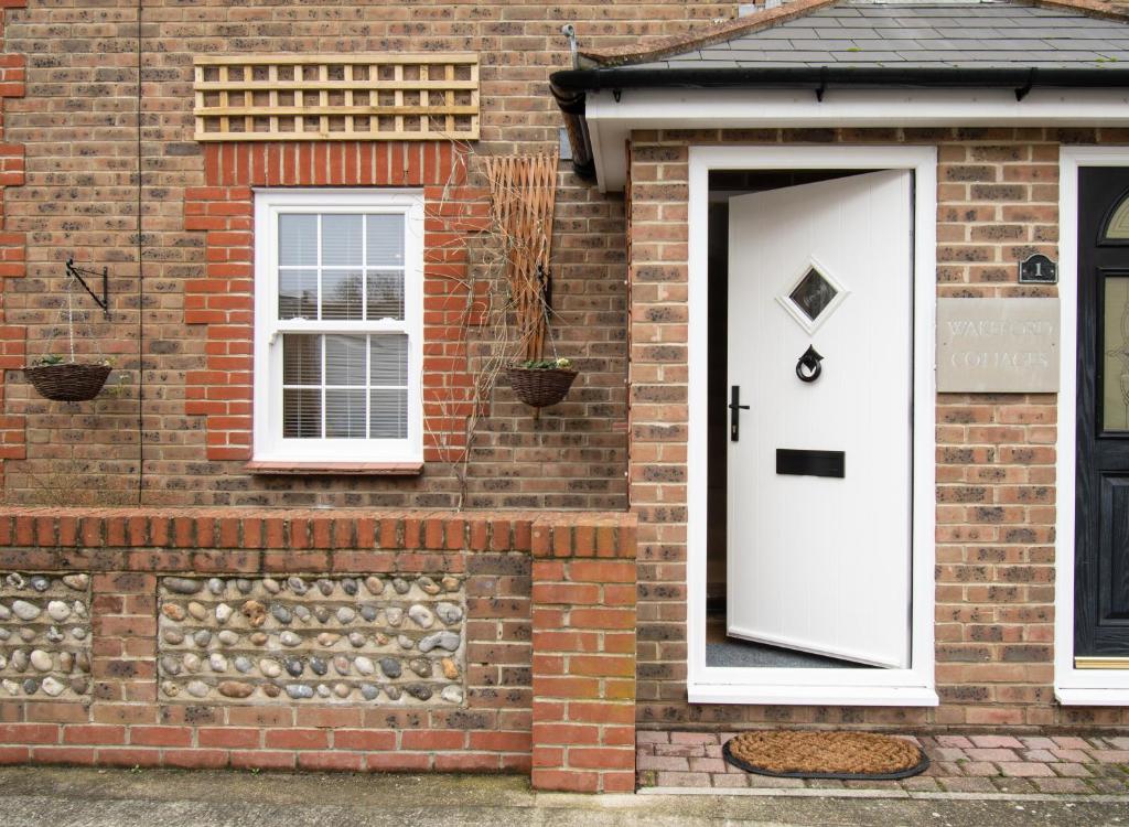 a brick house with a white door and windows at Wakeford Cottage in Worthing