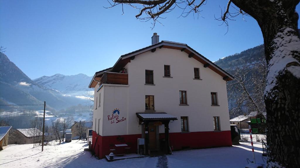 ein großes weißes Gebäude mit Schnee auf dem Boden in der Unterkunft Relais del Sosto in Olivone