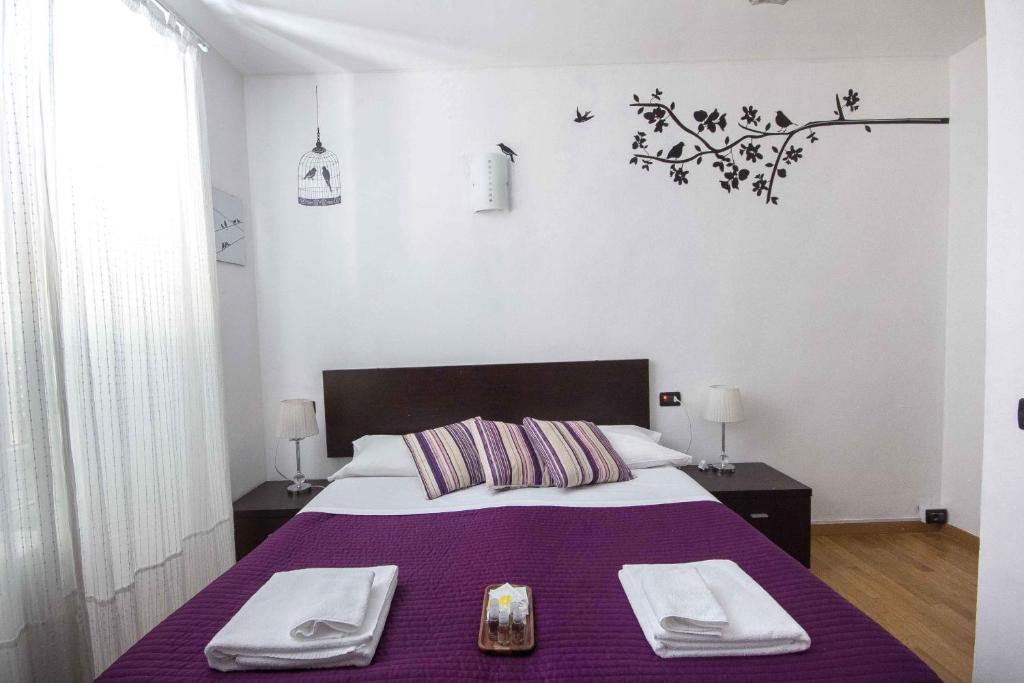 1 dormitorio con 1 cama morada y 2 toallas en Affittacamere The Tramp, en La Spezia