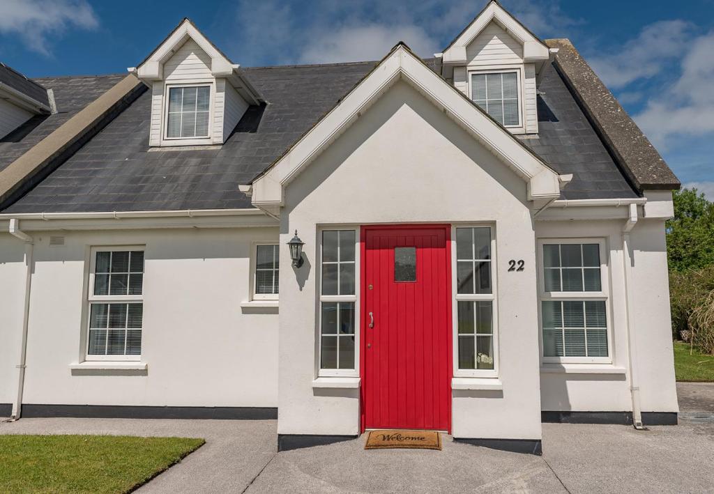 una casa con una puerta roja en una entrada en Ballybunion Cottages No 22 en Ballybunion