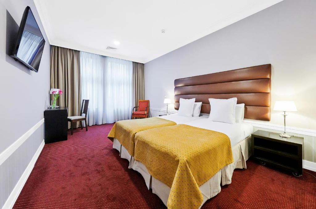プラハにあるラ ブティックの大型ベッドとテレビが備わるホテルルームです。