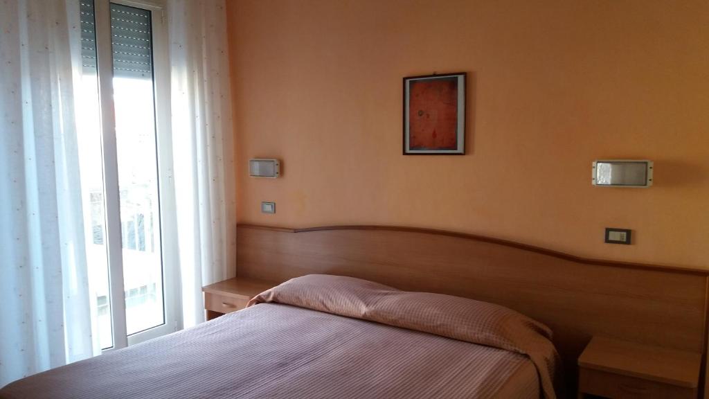 a bedroom with a bed and a large window at Albergo Moretti in Senigallia