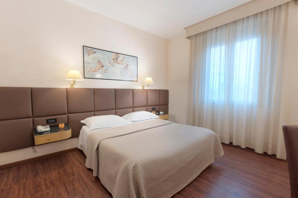 a hotel room with a large bed and a large window at Hotel Minerva in Arezzo