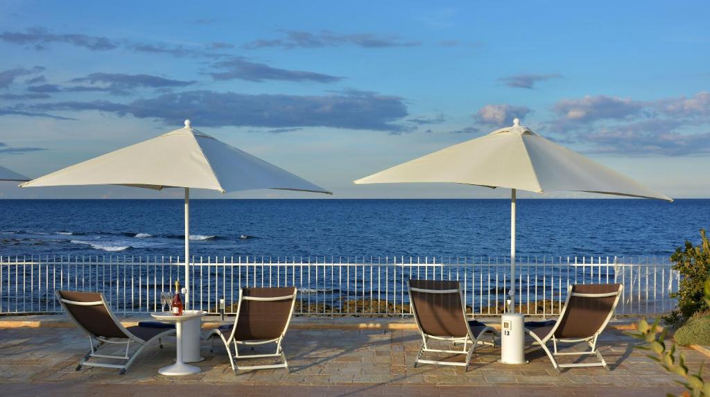 un gruppo di sedie e tavoli con ombrelloni sulla spiaggia di Vilu Suite Mare a Polignano a Mare