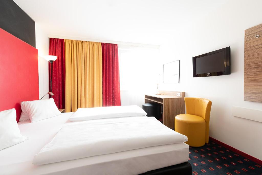 
a hotel room with two beds and a television at Senator Hotel Vienna in Vienna
