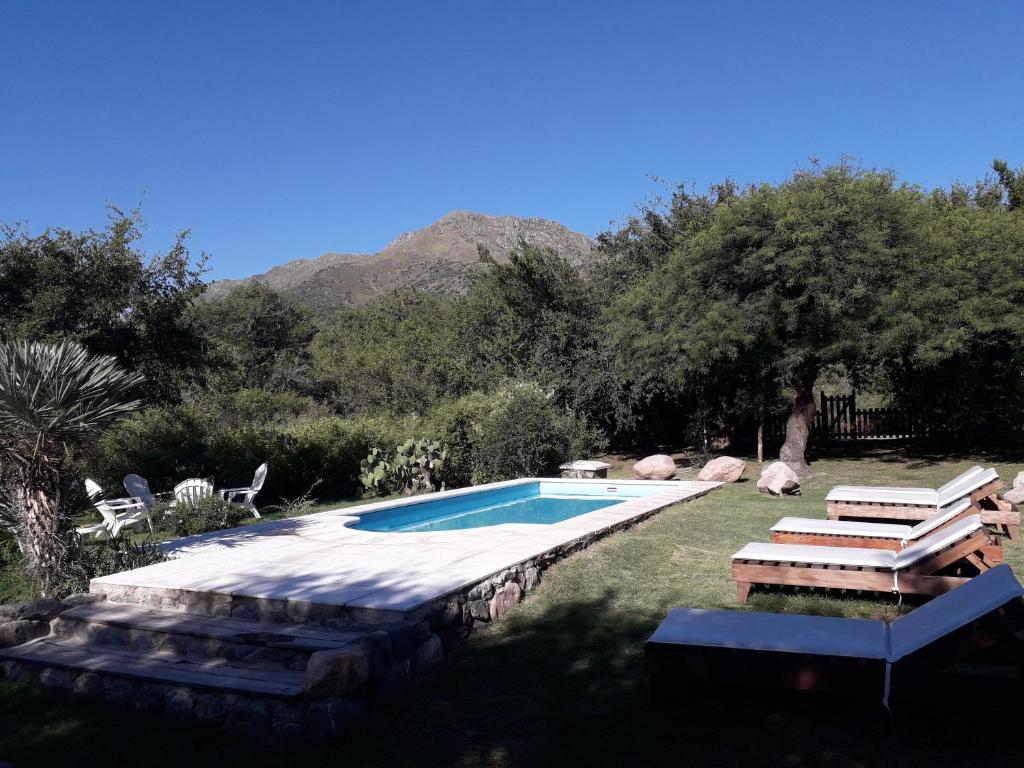 una piscina en un patio con sillas y árboles en Monte Capilla en Capilla del Monte