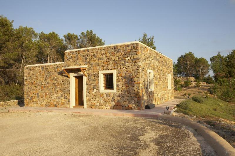 a stone building with a door in a field at Can Vich Petit in Sant Carles de Peralta