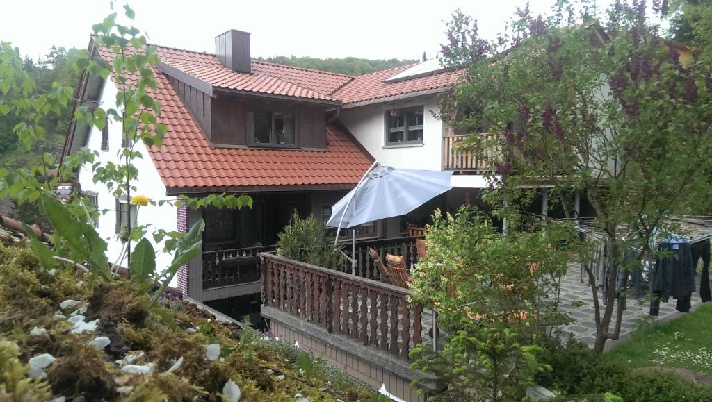 a house with a balcony and an umbrella at Pension Frauenschuh in Hirschbach
