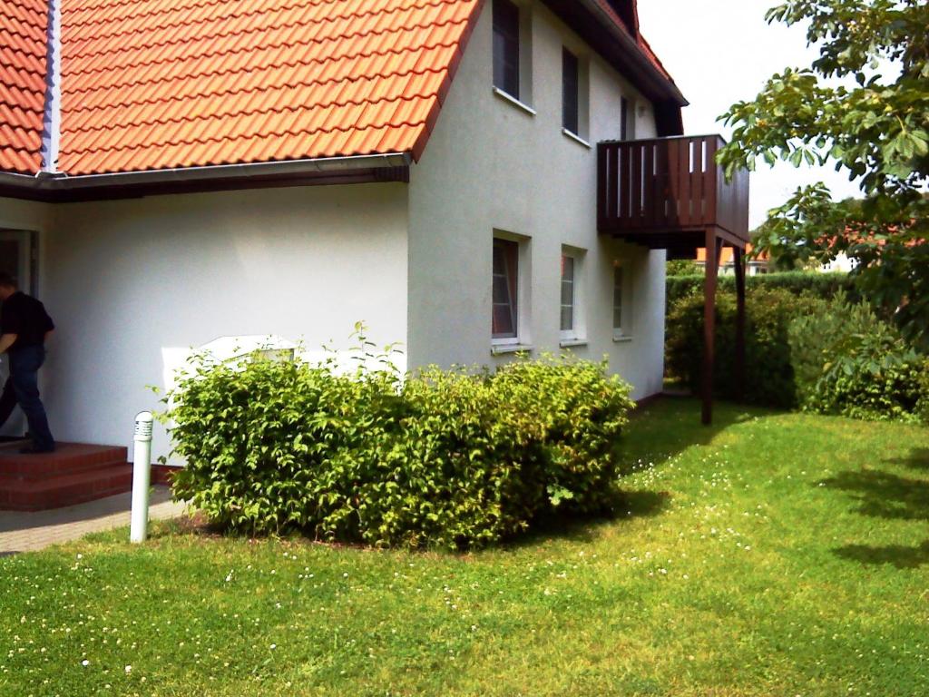 ein weißes Haus mit orangefarbenem Dach und einem Balkon in der Unterkunft K&S Ferienwohnungen in Dierhagen