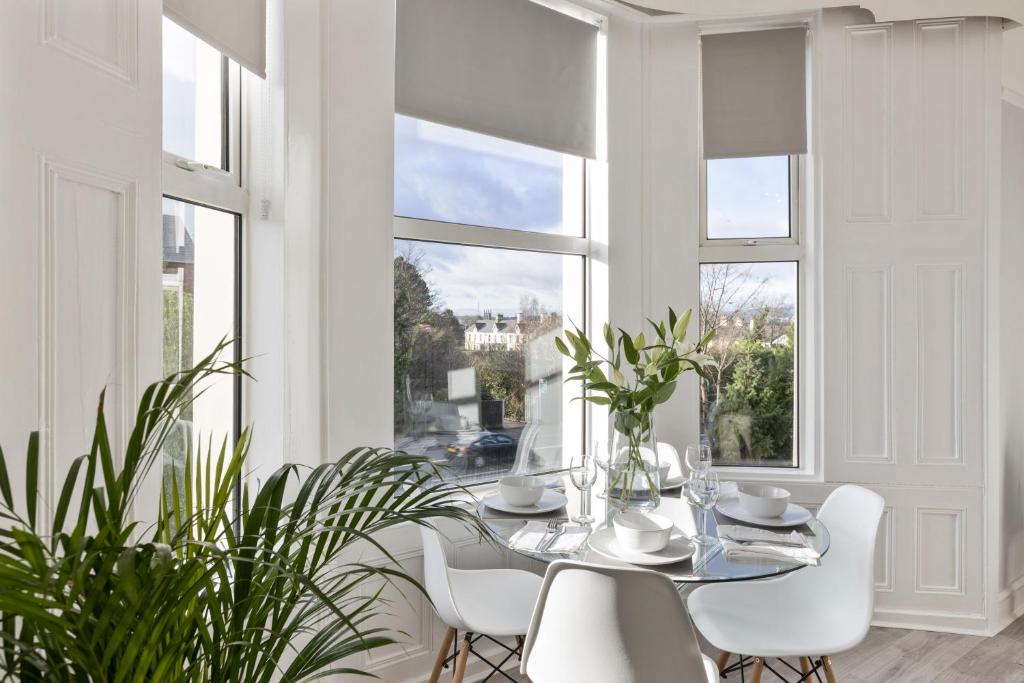 a dining room with a table and chairs and windows at Cyprus View Apartment 2 in Belfast