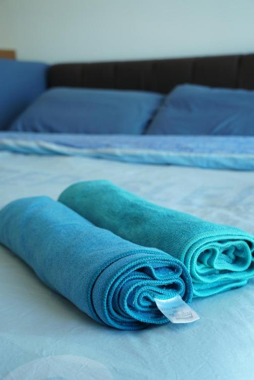 Una toalla azul enrollada en una cama en 2 Carpark GEP 5 Star Hotel Bed & Sofa Studio, en Seri Kembangan