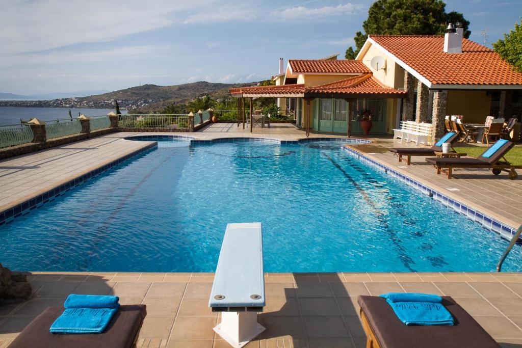 a swimming pool with chairs and a house at Aelia & Melitta Villas in Perdika