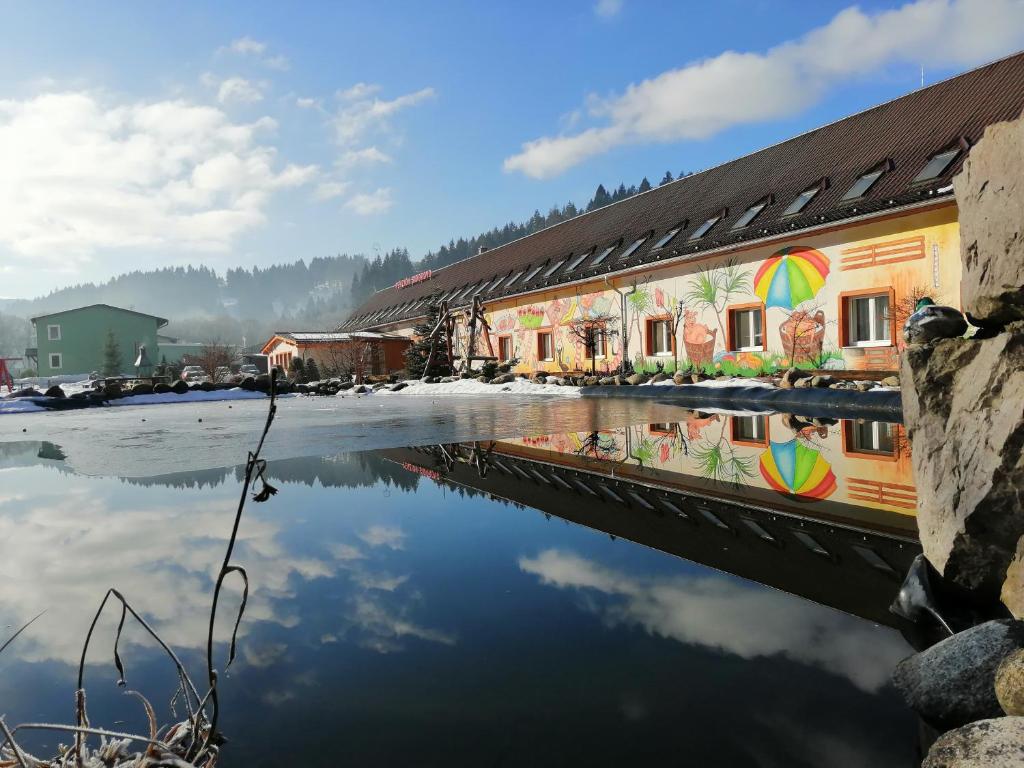 a building with a reflection in a body of water at Penzion Sidorovo in Ružomberok