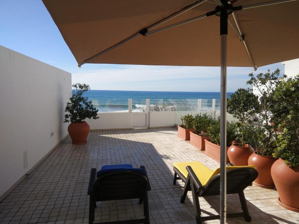 a patio with a table and chairs and an umbrella at Ribalta Beach Houses in Ericeira