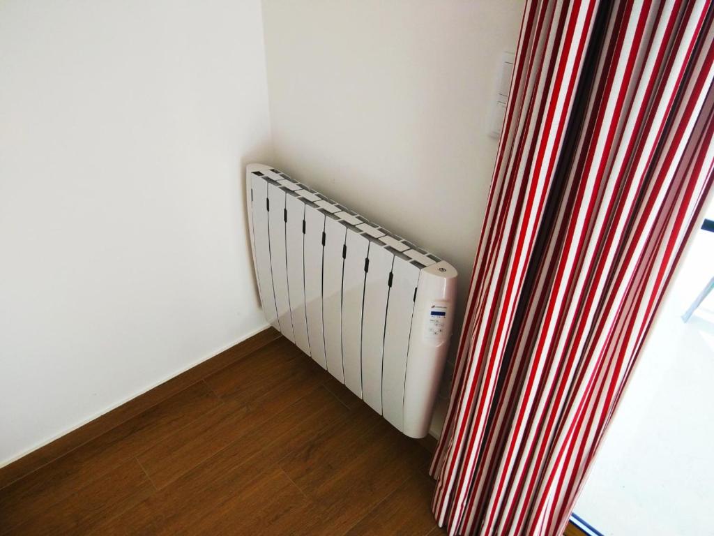 a radiator in a room with a red and white curtain at Ribalta Beach Houses in Ericeira