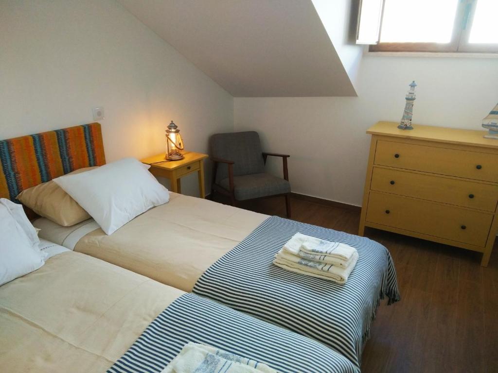 a bedroom with two beds and a chair and a dresser at Ribalta Beach Houses in Ericeira