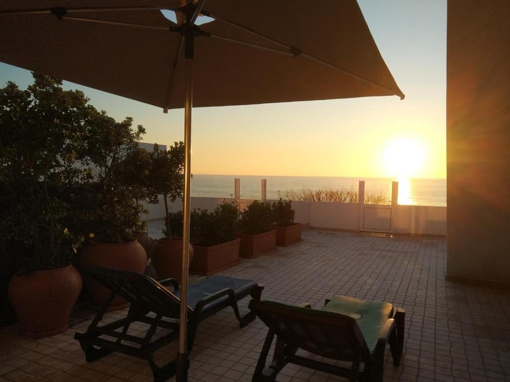 a patio with two chairs and an umbrella at Ribalta Beach Houses in Ericeira