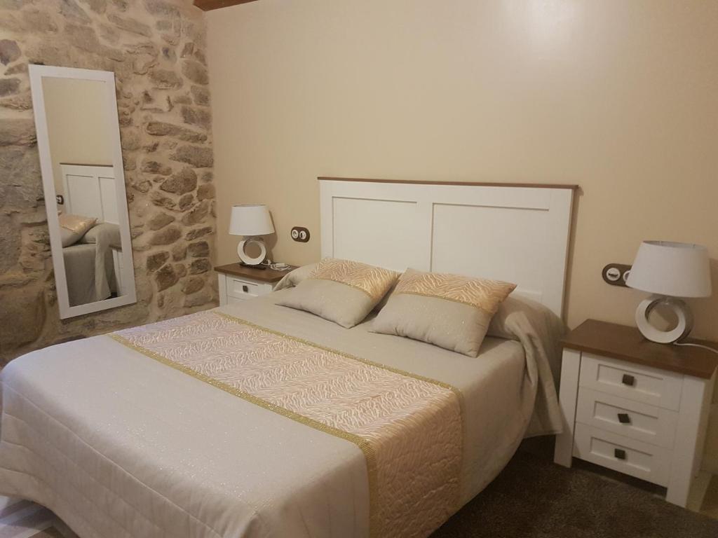 een slaapkamer met een bed met 2 lampen en een spiegel bij Casa Mariñeira in Combarro