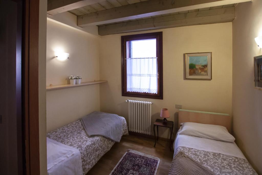 2 łóżka w małym pokoju z oknem w obiekcie Venice Apartment w Wenecji