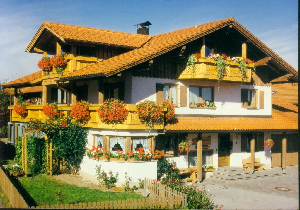 a large yellow house with flowers in the windows at Gästehaus Kerpf inclusive KönigsCard in Nesselwang