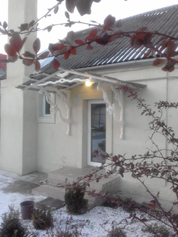 a white house with a window and a tree at Гостьовий дім у Почаєві in Pochayiv