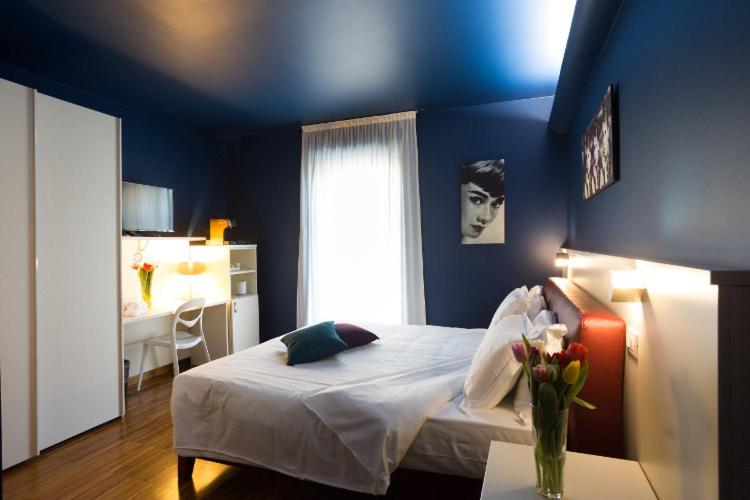 una camera blu con un letto e un vaso di fiori di Albergo Residenza Al Teatro a Udine